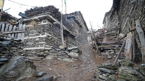 Stone buildings flank a narrow, rocky alley in a mountain village, trekking at Annapurna Circuit,
