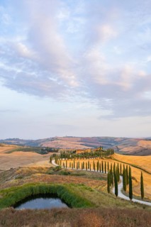 Typical Tuscan landscape in Crete Senesi with hills, trees, fields, cypresses and farm road in