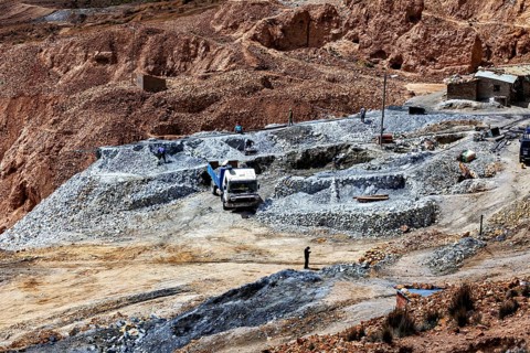 Different vehicles on a mining site with visible piles of stones and roads, The silver mines of