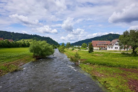 River Kinzig, hilly landscape with forest, meadow and trees, blue sky with cumulus clouds,