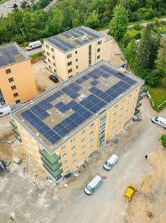 Aerial view shows buildings with solar panels on the roofs, construction site with several vehicles