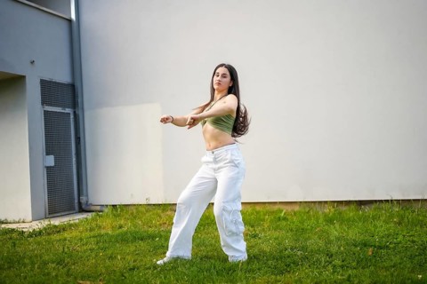 Beauty caucasian young female dancer performing modern choreography outside a building with grass