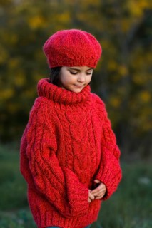 A young girl in a vibrant red woolen hat and sweater is pictured during a serene autumn day, with