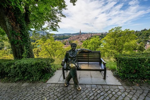 Albert Einstein sitting on a bench, bronze figure of Le Passioni, view of the old town from the