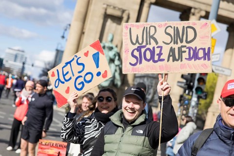 People holding signs Let's go! and We are proud of you at the 44th Generali Berlin Half Marathon