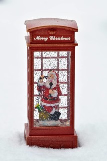 Christmas decoration, Father Christmas standing in snowfall in telephone booth making phone call