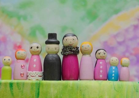 Nine funny painted wooden cones man and woman large and small in front of a colourful painted
