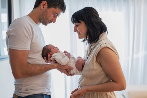 A loving father and mother embrace their newborn baby in a bright room, sharing a joyful and