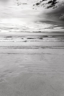 Coastline, sandy beach, sand ripples, shore, view of the sea, dramatic cloudy sky, monochrome,