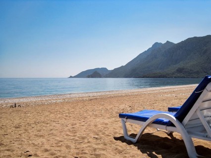 Picturesque beach of Çirali on Turkey's Mediterranean coast with an empty blue sun lounger and