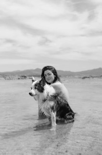 A woman and her dog relax in the shallow waters of a serene beach The black and white image