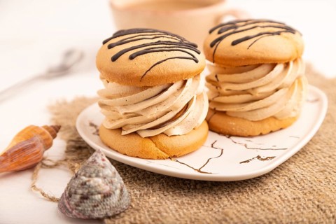 Caramel Cream Cakes on white wooden background and linen textile, cup of coffee, side view, close