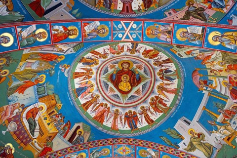 Colourful ceiling painting with holy icons and scenes on a blue background in a church, interior of