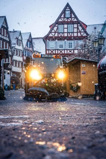 Clearing vehicle at work at a Christmas market during a snowfall in the evening, Black Forest,