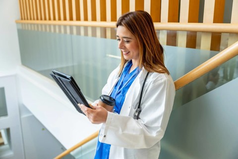 Young female medical professional reviewing information on a digital tablet and holding a