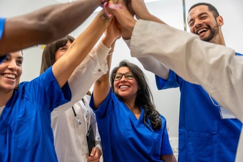 Medical team of doctors and nurses sharing a celebratory high five in a hospital, expressing