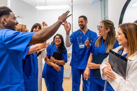 Diverse team of doctors and nurses in scrubs celebrating a successful collaboration with smiles and