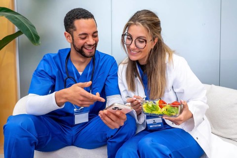 Healthcare professionals relaxing during a break, sharing a mobile device screen while one is