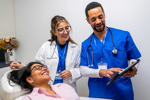 Healthcare professionals consulting with a happy female patient in a medical office, explaining
