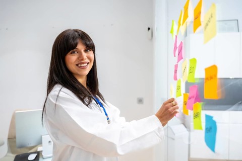 Female doctor in a white coat smiling confidently, organizing and analyzing various healthcare