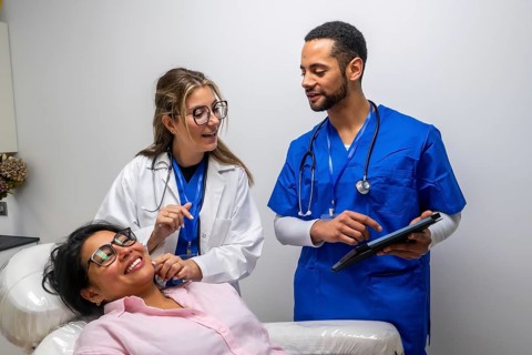 Healthcare staff, including a doctor and nurse, are discussing medical information with a smiling