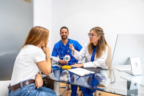 Medical team consisting of a female optometrist and male nurse consulting a female patient about