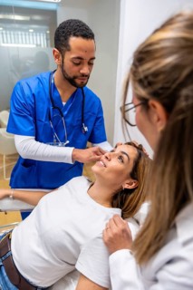Medical professionals examining a female patient's face and skin for a cosmetic procedure or