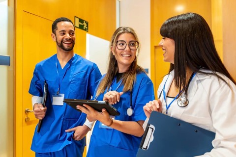 Healthcare team of doctors and nurses smiling and collaborating in a hospital hallway, reviewing a