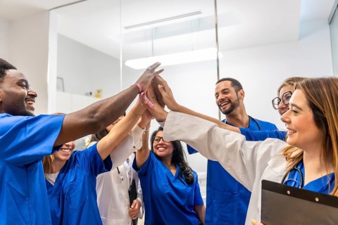 Diverse group of healthcare professionals celebrating their strong teamwork and success by putting