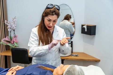 Medical professional in a white coat and gloves explaining a skincare or laser hair removal
