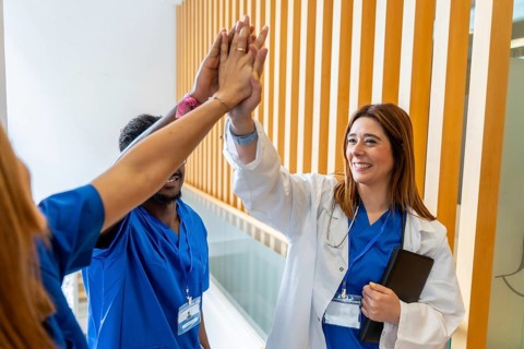 Diverse medical team members, including a female doctor and male nurse, celebrating success and