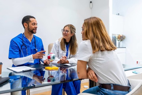 Medical professionals discussing eye health with a female patient using an anatomical eye model