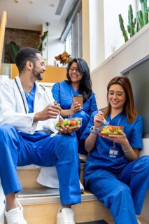 Healthcare professionals sitting together in hospital, enjoying healthy salad meals and coffee