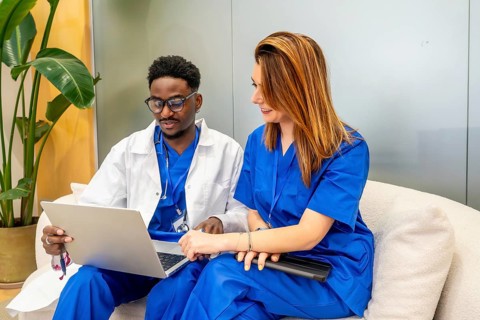 Diverse medical professionals wearing scrubs and lab coat collaborating while reviewing results on