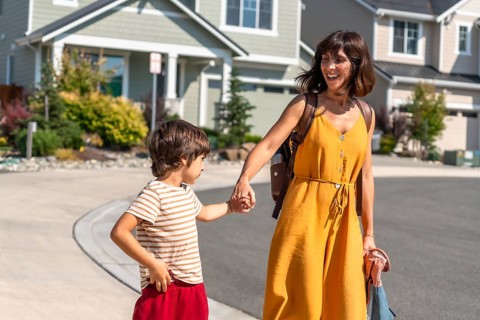 Happy mother and young son walking hand in hand on a sunny day, strolling through a quiet