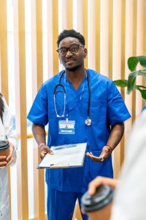 African american medical professional wearing blue scrubs and stethoscope, holding a clipboard,
