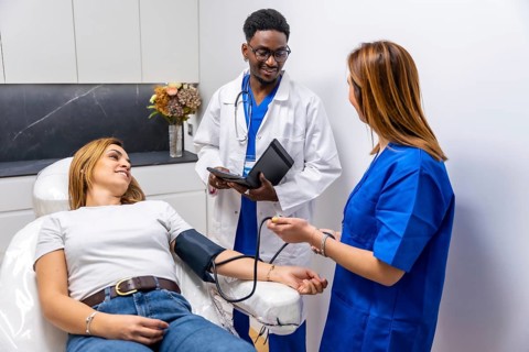 Medical professional team with a doctor and nurse performing a blood pressure check on a female
