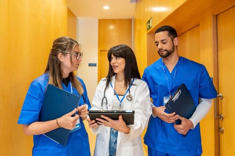 Healthcare professionals wearing scrubs and lab coat collaborating, discussing patient data on a