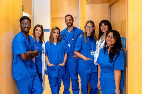 Group of diverse medical professionals including doctors and nurses wearing scrubs and lab coats.