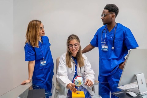 Medical students or young healthcare professionals are gathered around an eye model, actively