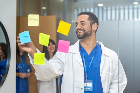 Doctor in medical uniform and lab coat brainstorming and organizing ideas on a glass wall with