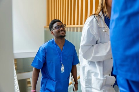 Healthcare professionals, including a male nurse in blue scrubs and a female doctor in a lab coat,