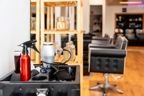 Styling tools and equipment arranged on a barber cart. Including a hair dryer and spray bottle.