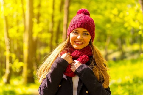 Latin girl with a black jacket, scarf and red woolen hat enjoying in an autumn park, portrait