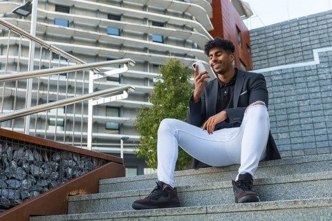 Low angle view of an Arab businessman sitting in outdoor stairs using phone