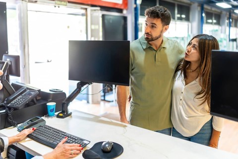 Young couple stands at a service desk receiving friendly advice from a store employee while
