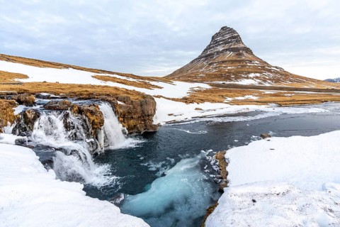 Beautiful waterfall with snow on the famous Kirkjufell mountain in winter in Iceland