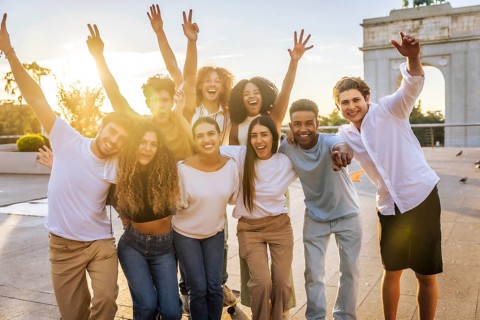 Formal portrait of a group of multi-ethnic friends raising arms enjoying together in the city