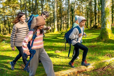 Side view full length of a happy caucasian family trekking in a green alpine forest