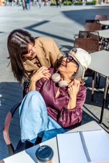 Two women sharing a joyful and strong connection, with one embracing the other from behind,